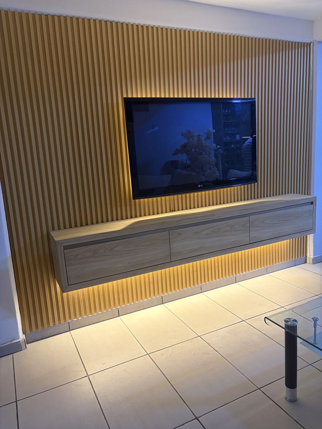 Muro de TV con panel ranurado y mueble flotante iluminado